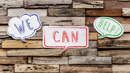 Speech bubbles on wooden background : we can help