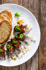 Marinated herring fillets with slices of bread on white plate on wooden table