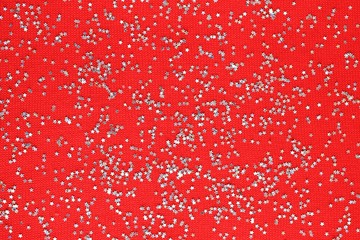 Top view with christmas silver stars. Silver stars confetti on a red knitted background. New year, christmas background.