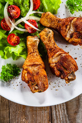 Grilled chicken drumsticks and vegetables on white plate