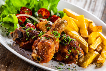 Grilled chicken drumsticks with french fries and vegetables