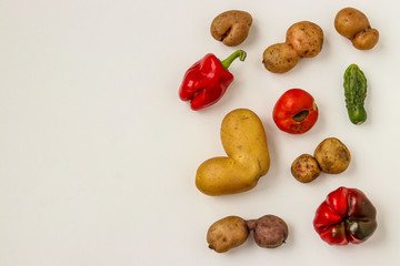 Trendy Ugly Organic Vegetables: potatoes, cucumber, peppers and tomatoes on white background, ugly food concept, horizontal orientation, Copy space, Closeup