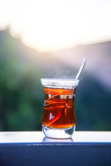 Oriental Asian Arabic Turkish Tea Glass Cup on Edge with Natural Mountain Background 