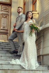 Caucasian romantic young couple celebrating their marriage in city. Tender bride and groom on modern city's street. Family, relationship, love concept. Contemporary wedding. Happy and confident.