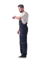 side view. a man in overalls looking at his wristwatch