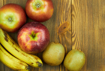 Close up view of red apples, bananas and kiwi on wooden background with copy space for text. Still life of fresh fruits
