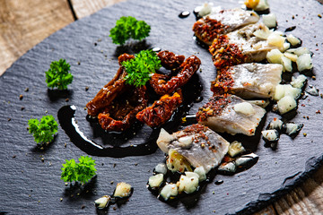 Marinated herring fillets on black stone