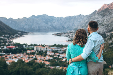 A couple of tourists hug and enjoy the beautiful view of the Kotor Bay and the city of Kotor in Montenegro. Travel together.