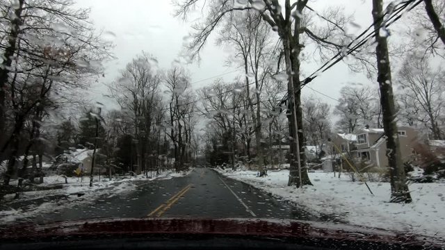 driving through suburban area on a gloomy rainy-snowy early spring day