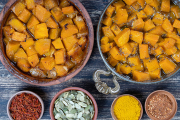 Baked yellow pumpkin with honey, anise, olive oil and spices on a plate on the wooden table. Vegetarian food. Closeup