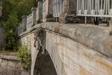Unusual old bridge overgrown with moss and with a lion's head