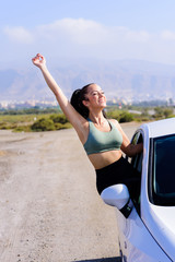 Portrait of happy young woman going on a road trip leaning out of window
