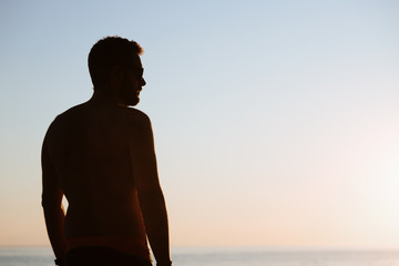 Young man looking at sunset by the sea