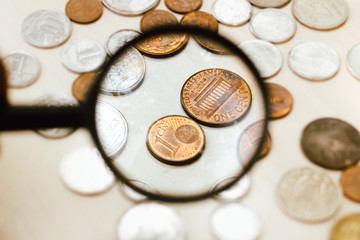 Euro 1 (one) cent coin seen through a magnifying glass - coins on table - economy and finance concept.