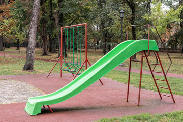 Playground in the park with a rubberized floor under the shell g