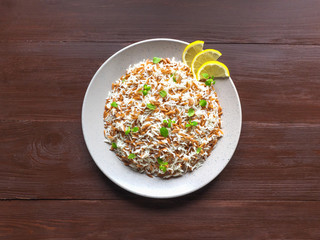 Turkish rice pilaf with orzo in a plate on a brown wooden background. Top view