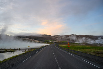 Fototapeta premium Empty road in Iceland at Hverir geothermal area with hot steam during sunset