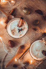 Fototapeta na wymiar Eggnog in glasses with star anise and cinnamon on wooden table for Christmas and winter holidays. Copyspace included.