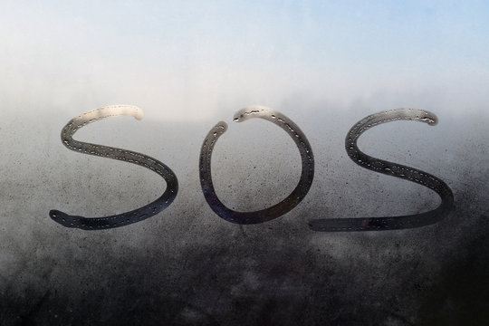 SOS text. Inscription on sweaty window. Written message on steamy window. 