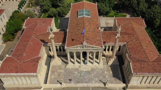Aerial video of famous trilogy landmark buildings of Academy of Athens, Panepistimio or University, public Library with iconic Lycabettus hill at the background, Athens, Attica, Greece