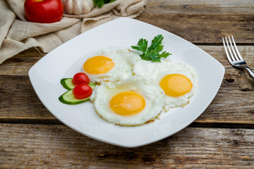Fried eggs with tomatoes on wooden table