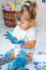 Little cute girl draws with finger paints on the floor. Early development concept