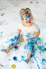 Little cute girl draws with finger paints on the floor. Early development concept