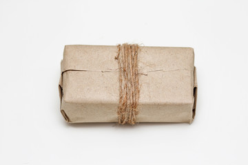 Parcel wrapping in brown craft paper and tie hemp string. Package. Delivery service. Online shopping. Your purchase. Gift box on a table. Isolation on white. 