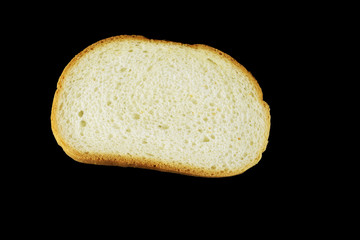 One piece of long loaf bread isolated on black. Top view