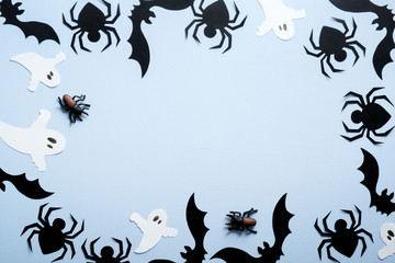 Happy halloween holiday concept. Halloween decorations, spiders, bats, ghost on blue background. Flat lay, top view, overhead.
