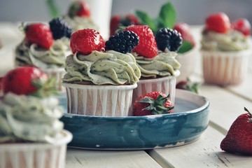 Strawberry cupcakes and green leaves on wooden background