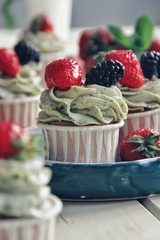 Strawberry cupcakes and green leaves on wooden background