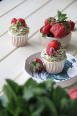 Strawberry cupcakes and green leaves on wooden background