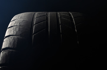 Old damaged, worn black tire tread, large cracks in the car wheel, tire black color for background.