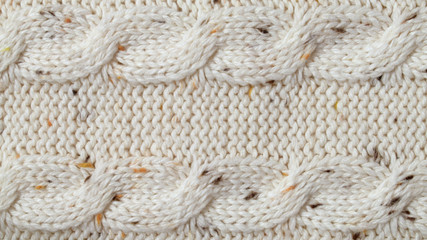 Beige melange yarn knitted texture background. Purl and cables