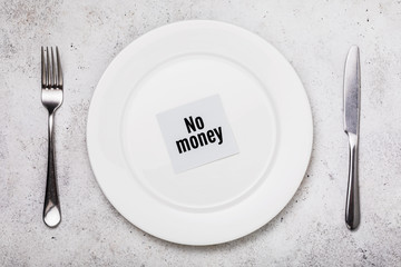 Concept on the lack of money for food. Cutlery and empty white plate on the table, top view