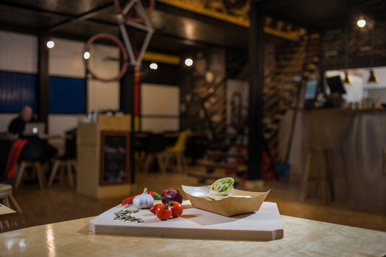 Appetizing fast food on a wooden board with fresh vegetables.