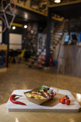 Appetizing fast food on a wooden board with fresh vegetables.