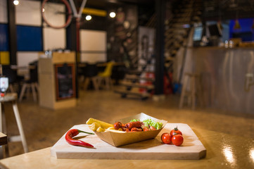 Appetizing fast food on a wooden board with fresh vegetables.