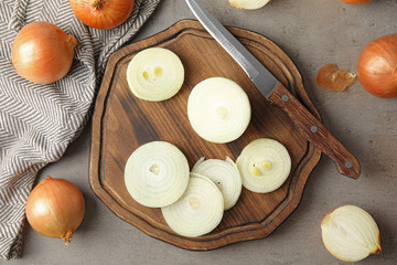 Flat lay composition with cut and whole onions on grey table