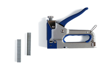 Metal furniture stapler and staples with shadows isolated on a white background.  Staple gun.