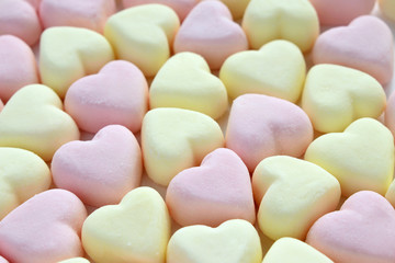 Light pink and yellow heart shape souffle candies. Closeup. Sweets background