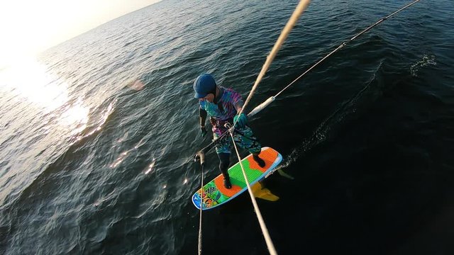 Excited man is kiteboarding across the water