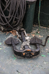 Old steel anchor on deck and black rope