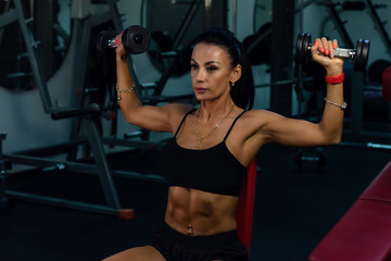 Fototapeta na wymiar a beautiful hot sportive girl with a nice abs in the gym. bodybuilding. a hot brunette is training, doing workout. fit girls. hot woman