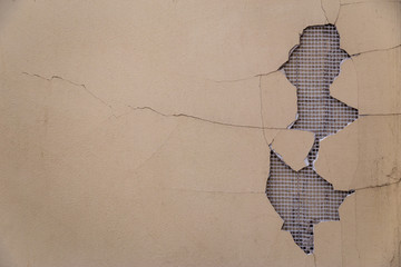 Big stucko fail on the wall with pavement crack and lattice holding bricks seen from the back.