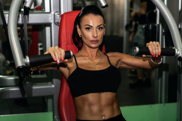 Fototapeta na wymiar a beautiful hot sportive girl with a nice abs in the gym. bodybuilding. a hot brunette is training, doing workout. fit girls. hot woman