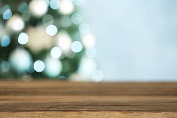 Empty wooden table and blurred fir tree with Christmas lights on background, bokeh effect. Space for design