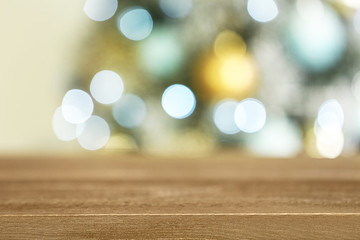 Empty wooden table and blurred fir tree with Christmas lights on background, bokeh effect. Space for design