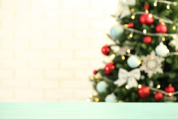 Empty wooden table against fir tree with Christmas lights, blurred view. Space for design